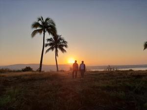 two people standing in front of a palm tree at sunset at Casa Vista Hermosa in Vista Hermosa