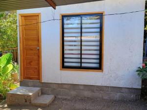 维库尼亚Cabaña Peralillo的一座带窗户和木门的建筑