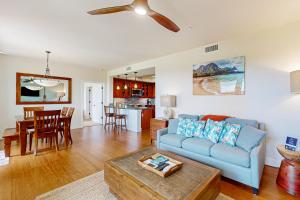 Una sala de estar con un sofá azul y una mesa. en Pili Mai 7H, en Koloa