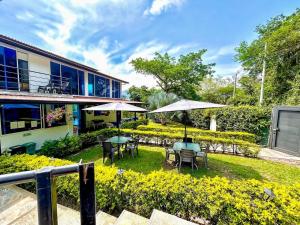 a garden with tables and umbrellas in front of a building at Hotel Zipa Villeta - Sede Campestre in Villeta