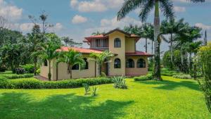 a house with a palm tree in a yard at Arenal Tropical Home Villa in Fortuna