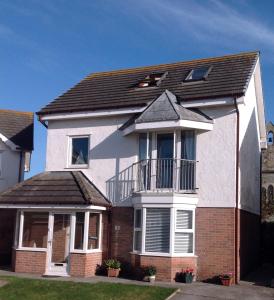 a white and red house with a balcony at Glasfor by the beach at Trearddur Bay in Trearddur