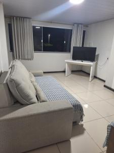 un soggiorno con un divano e una scrivania con una televisione di Casa para temporada Balneário de Carapebus a Serra