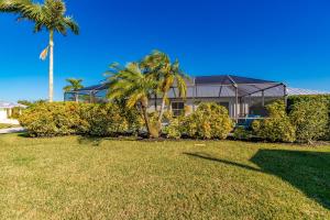 a house with palm trees in front of a yard at Fishtail Getaway in Sebastian