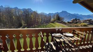 a table on a balcony with glasses of wine at Appartement cosy avec vue in Ollon