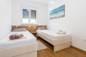 two beds in a room with white walls at Holiday House Libra in Jadrija