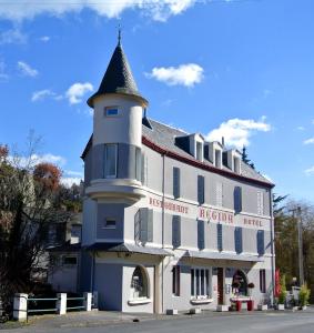 un grand bâtiment blanc avec une tour d'horloge. dans l'établissement Hotel Regina, à Saint-Nectaire