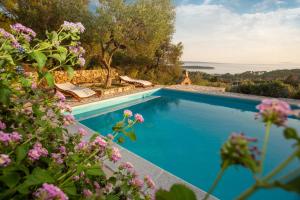 a pool with a view of the ocean and flowers at Villa Mora in Banjol