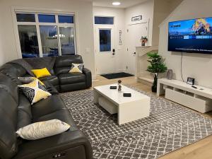 a living room with a black leather couch and a tv at Luxurious, Centrally Located Home in Cavanagh in Edmonton
