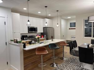 a kitchen with a counter and stools in a room at Luxurious, Centrally Located Home in Cavanagh in Edmonton