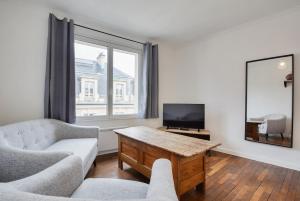een woonkamer met een bank, een tafel en een tv bij Appartement Place Stanislas 4eme in Nancy