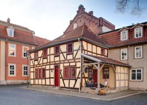 a building with red windows and a man sitting in front of it at Historisches Apartment in Mühlhausen Thuringia in Mühlhausen