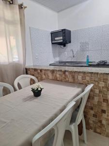 a kitchen with a table with chairs and a microwave at Caminho da Praia in Parati-Mirim +3 photos