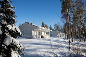 a white house in the snow with trees at Kajaani Cottages in Kajaani