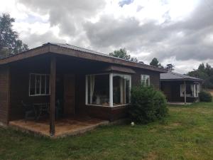 a small house with a porch and a large window at Cabañas Campos de Frutillar in Frutillar