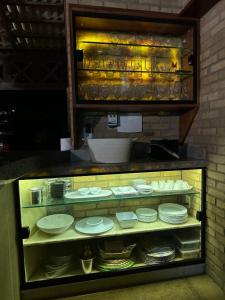 a display case with plates and dishes in it at Chalés em Flecheiras in Trairi