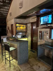 a kitchen with a bar with a tv on the wall at Chalés em Flecheiras in Trairi +8 photos
