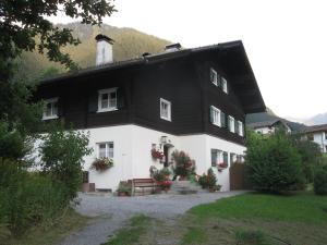a black and white house with a bench in front at Haus Klinger in Gaschurn