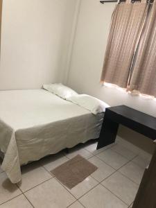 a bedroom with a bed and a table and a window at Quadra 6 Paiaguás Parque das Águas Cuiabá in Cuiabá