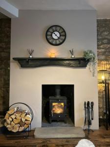 un soggiorno con camino e orologio a parete di Woodstock Cottage, Settle, Yorkshire Dales a Settle