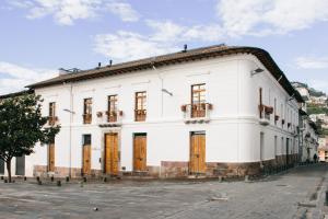 a white building with wooden doors on a street at Casa Santa Clara - Colonial Boutique Hotel in Quito