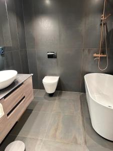 une salle de bains avec baignoire, toilettes et lavabo dans l'établissement Granåsen ski-VM, à Trondheim 7 autres photos