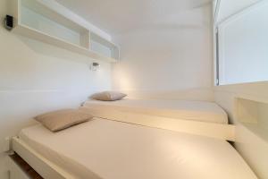 two beds in a small room with a window at La Cigale Varoise - Hyères La Plage in Hyères