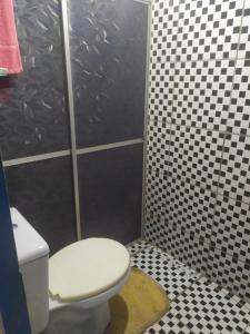 a bathroom with a toilet and black and white tiles at Lais in Lençóis