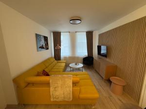 a living room with a yellow couch and a tv at The Hook Apartments in Dolný Kubín