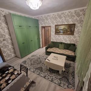a living room with a green couch and a table at Aviacity Apartment in Baku