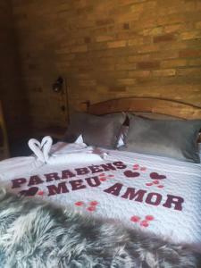 a bed with a white comforter with a happy new mom sign on it at Chalés Brisa Da Montanha in Sapucaí-Mirim
