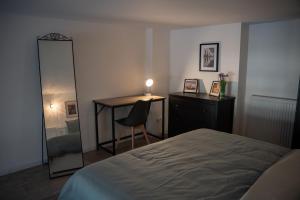 ein Schlafzimmer mit einem Bett, einem Schreibtisch und einem Spiegel in der Unterkunft Le Passementier, T2 duplex grand volume parking souterrain wifi Netflix in Saint Etienne
