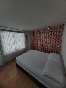 a small bedroom with a bed and a window at NômadeHostel - Vila Madalena in Sao Paulo