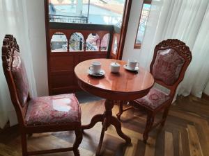 un tavolo di legno con due sedie e due tazze sopra di Kantu hotel a Cuzco