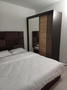 a bedroom with a large white bed and a mirror at Cozy Place in Craiova