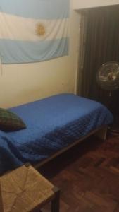 a bedroom with a bed with a blue blanket and a fan at Habitación single con baño privado en departamento compartido in Cordoba +4 photos