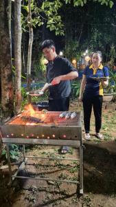 a man and a woman standing next to a grill at Valley Village Resort Phu Quoc in Phú Quốc