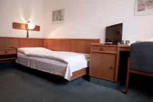 a bedroom with a bed and a desk with a television at Hotel Ungarische Krone in Bruckneudorf