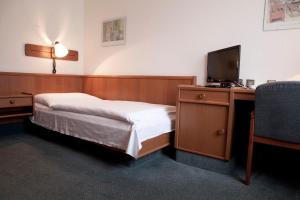 una camera con letto e scrivania con TV di Hotel Ungarische Krone a Bruckneudorf