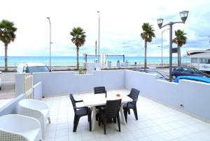 Un patio con mesa y sillas y el mar. en Capo d'Orlando Apartments - Relax Beachside, en Capo dʼOrlando