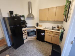 a small kitchen with a black refrigerator and a sink at L 'Échappée Cambrésienne in Cambrai