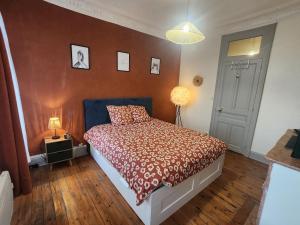 a bedroom with a bed with a red comforter at L 'Échappée Cambrésienne in Cambrai