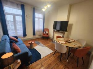 a living room with a blue couch and a table at L 'Échappée Cambrésienne in Cambrai