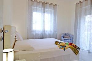 Un dormitorio con una cama blanca y una silla azul. en Capo d'Orlando Apartments - Relax Beachside, en Capo dʼOrlando