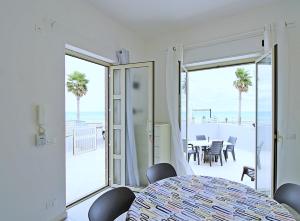 Habitación blanca con mesa y vistas al océano en Capo d'Orlando Apartments - Relax Beachside, en Capo dʼOrlando