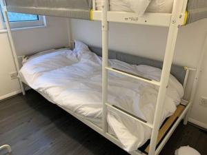 a bunk bed with white sheets on it at Byron View House in Luton