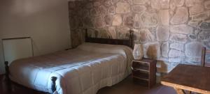 Un dormitorio con una cama y una pared de piedra. en La Clementina, en Tilcara 10 fotos más