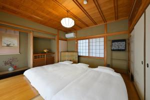 土庄町わとなみ的卧室里有一张白色的大床，床头板是木质的