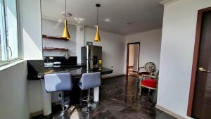 a kitchen with a counter with blue chairs and a refrigerator at Mimo Suits y Rooms in Machala