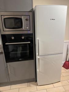 a microwave and a refrigerator in a kitchen at Cosy 2bed home near NEC BHX HS2 Business Park in Marston Green